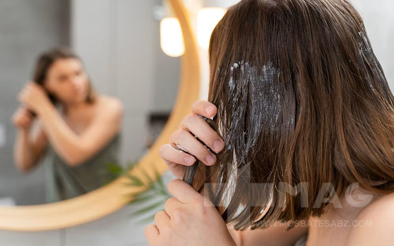 خانمی در حال زدن ماسک به موهای رنگ شده خود